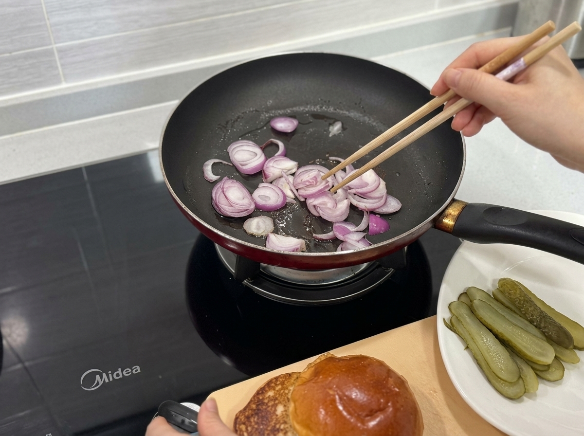 Fette di cipolla rossa saltate in una padella calda utilizzando bacchette di legno.