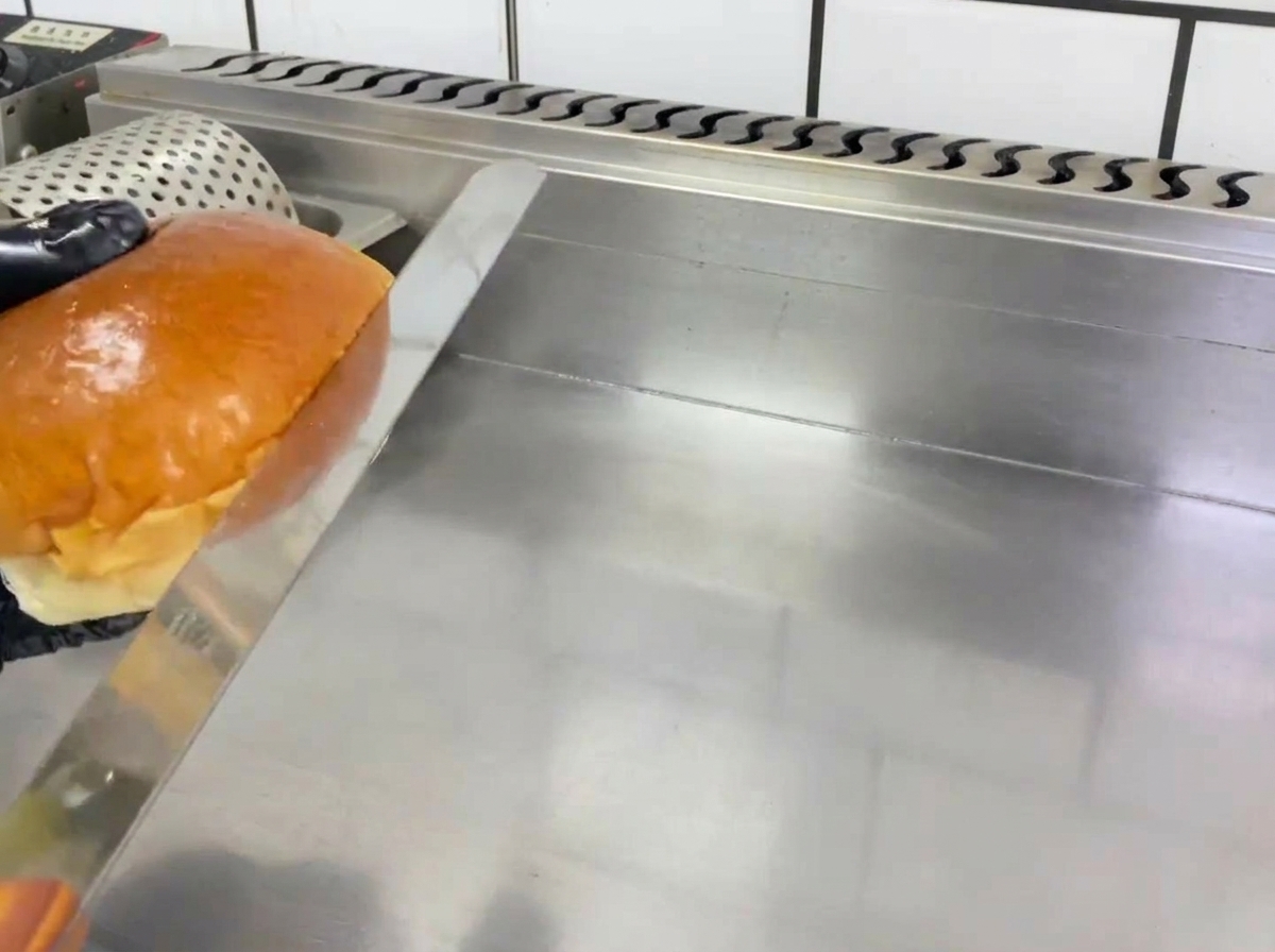 Metà di un panino per hamburger che tosta su una piastra rovente.