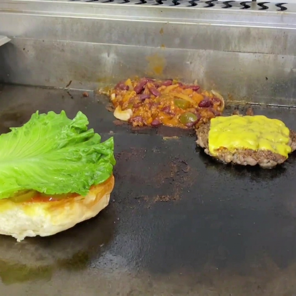 Lattuga e una fetta di pomodoro posizionate sulla base del panino tostato.