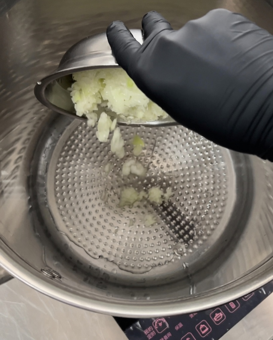 Cipolle finemente tritate rosolate in una grande pentola di acciaio inossidabile a fuoco medio.