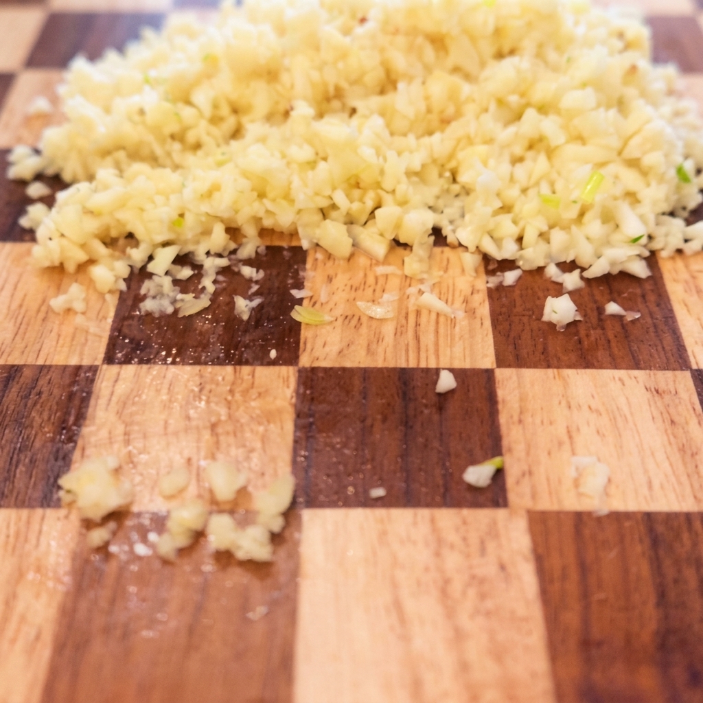 Peperoncini rossi arrostiti tagliati a segmenti più piccoli su un tagliere.