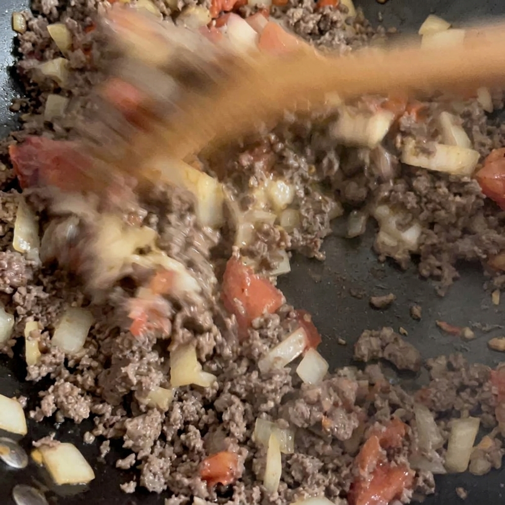 Manzo macinato rosolato e verdure saltate mescolati insieme in un wok.