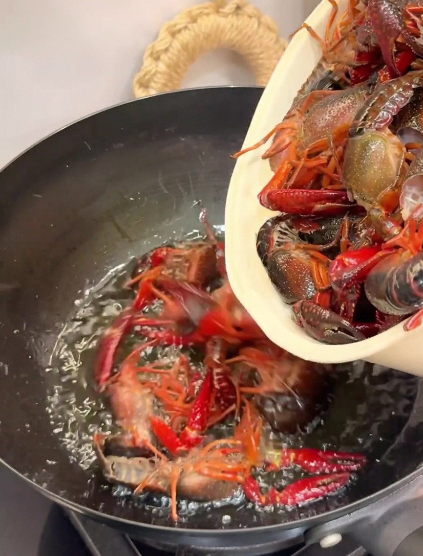 Gamberi di fiume versati in un wok caldo pieno dolio per la frittura.