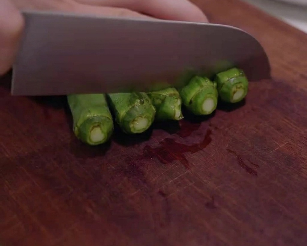 Okra verde fresca tagliata a rondelle su un tagliere di legno.