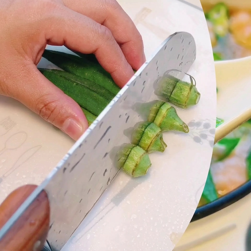Okra verde fresca tagliata con cura in sezioni più piccole e uniformi su un tagliere.
