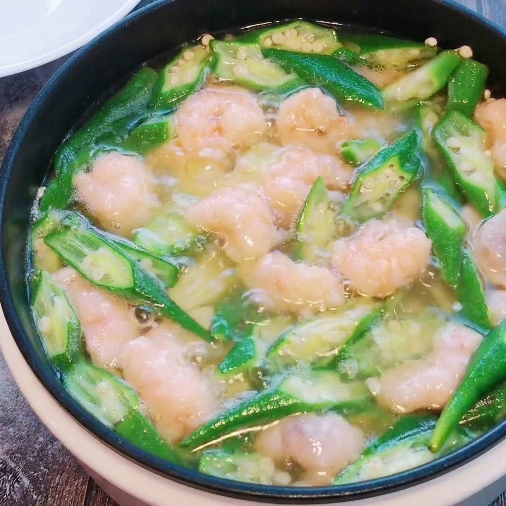 Le polpettine di pasta di gamberi mescolate delicatamente nella zuppa di okra e tofu mentre cuociono.