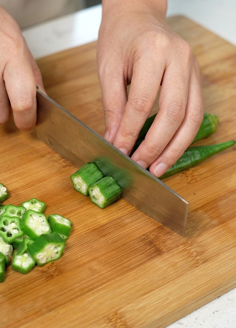 Lokra viene tagliata a rondelle su un tagliere di legno.