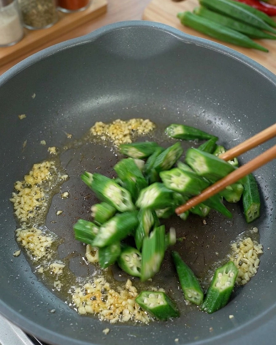 Okra affettata che viene saltata in padella con zenzero e olio.