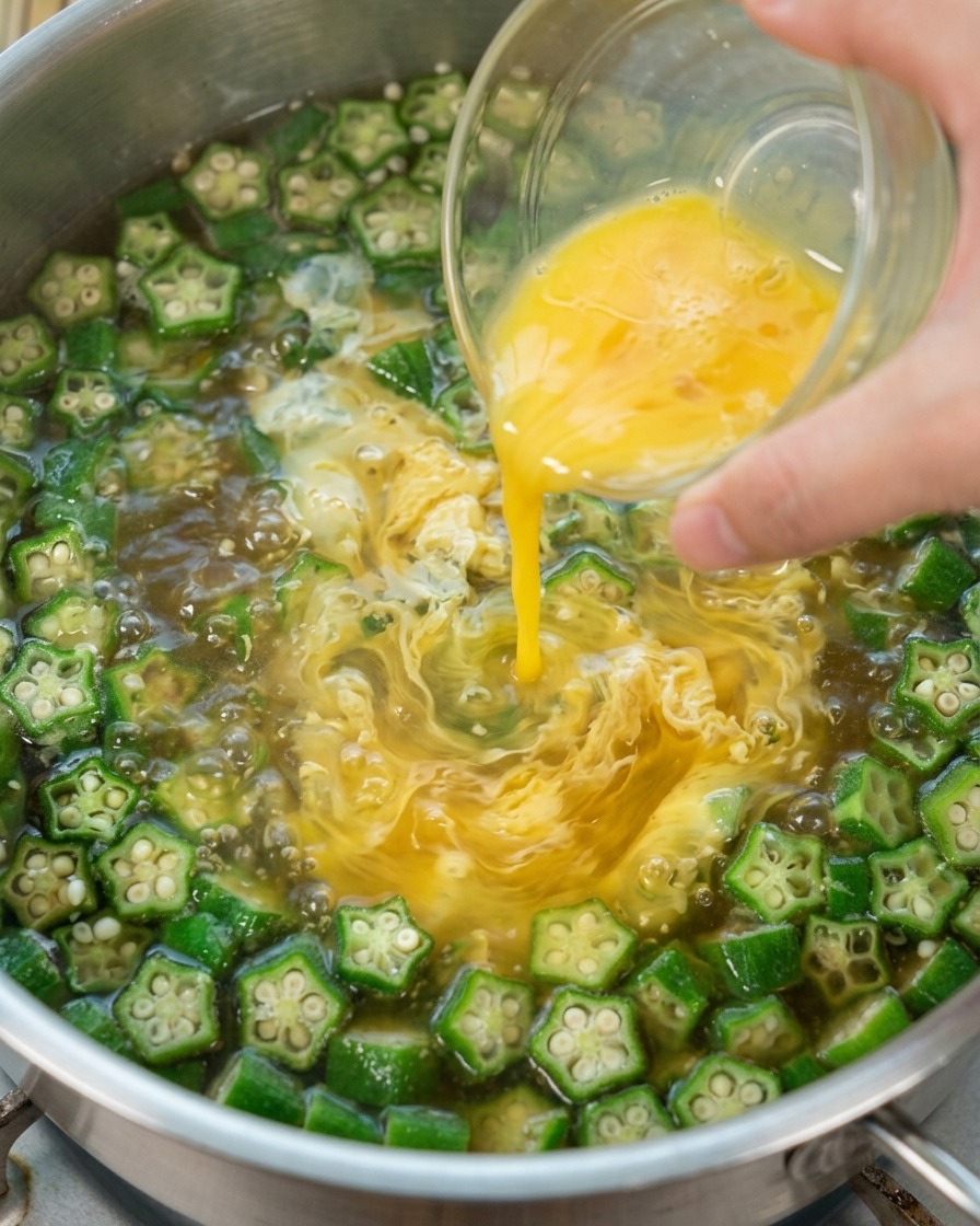 Uovo sbattuto versato nella zuppa di okra bollente per creare dei nastri.