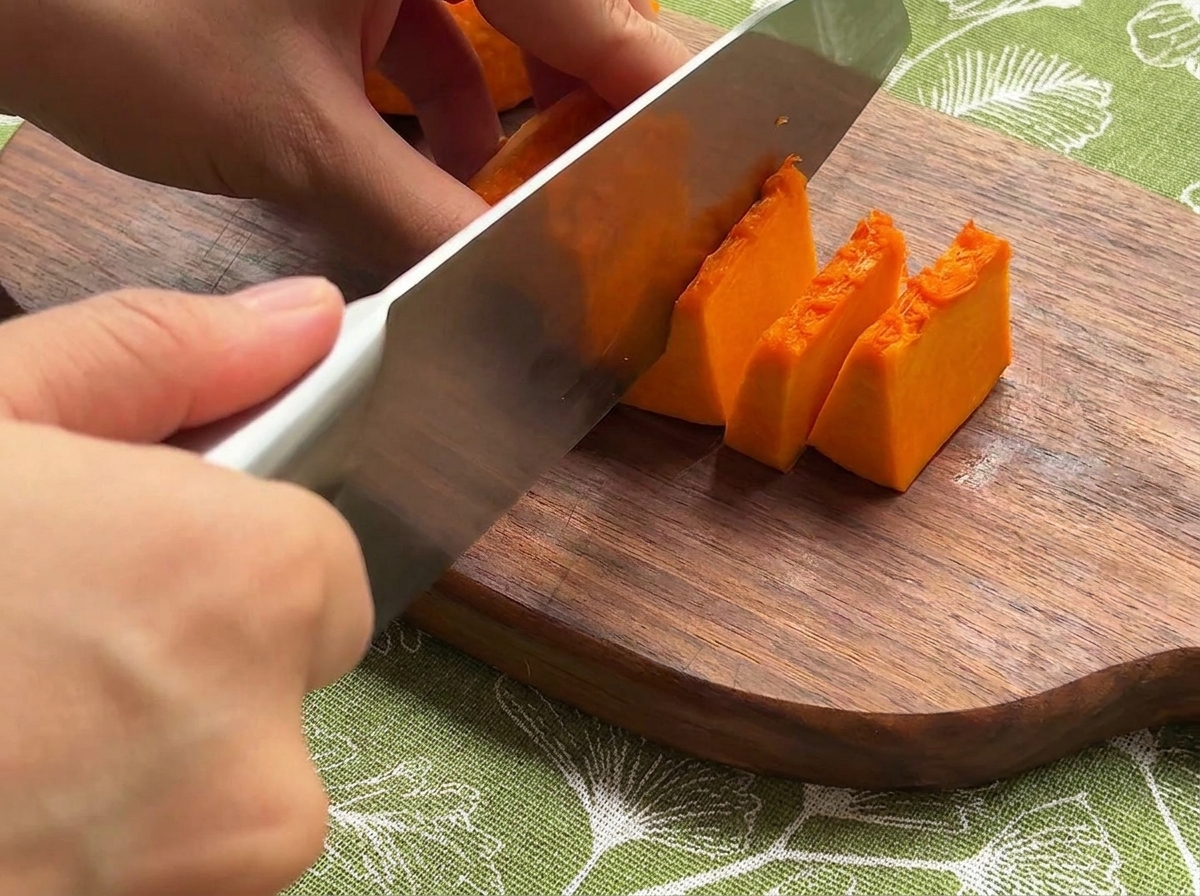 Zucca fresca, cipolla e carote tagliate a piccoli pezzi uniformi su un tagliere di legno.