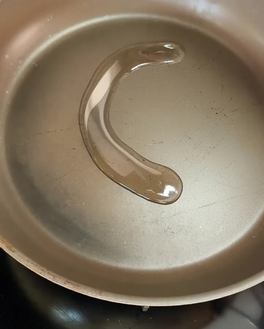 Fette di cipolla gialla che sfrigolano in padella con olio doliva.