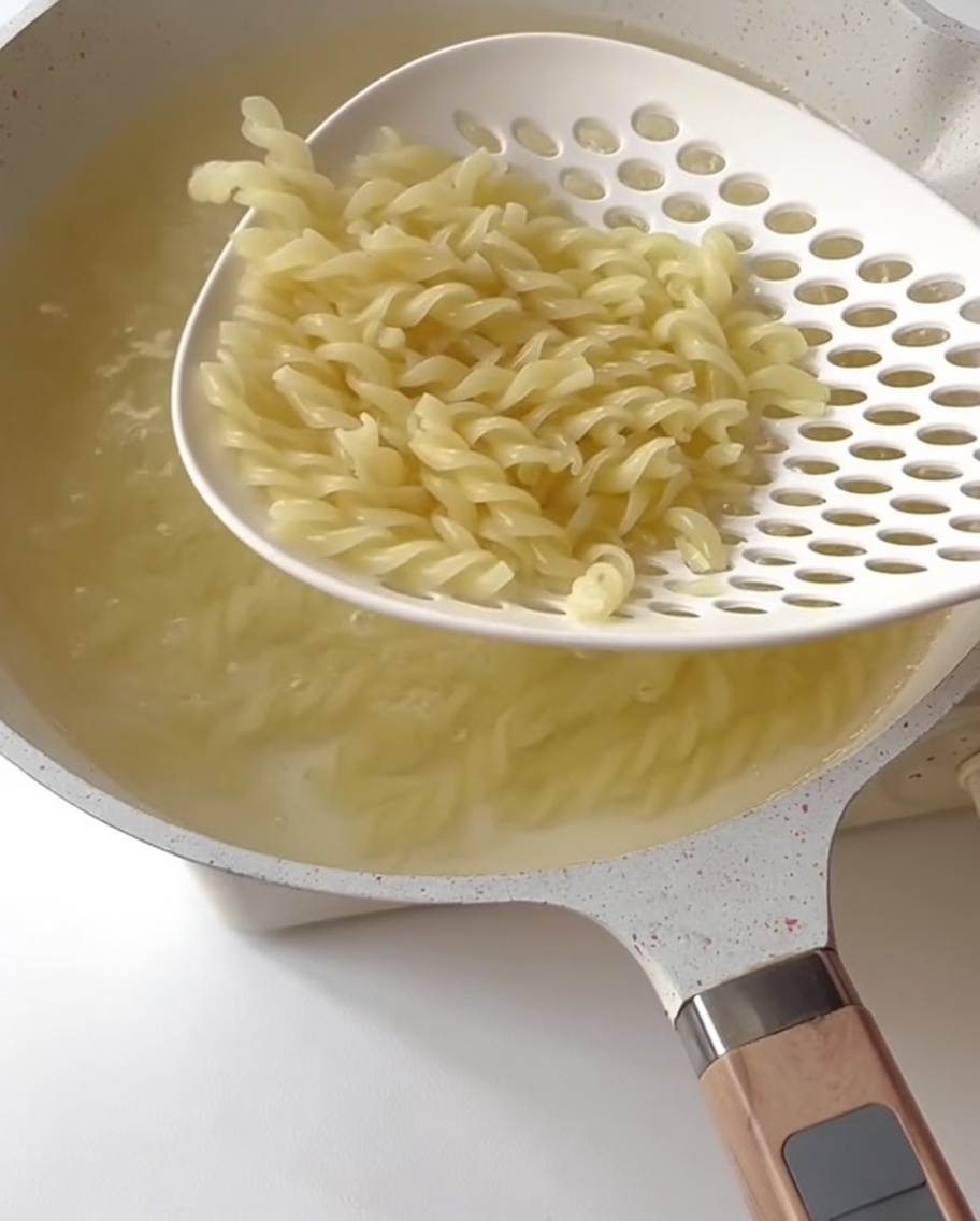 Pezzetti di asparagi verdi che cuociono in acqua bollente.