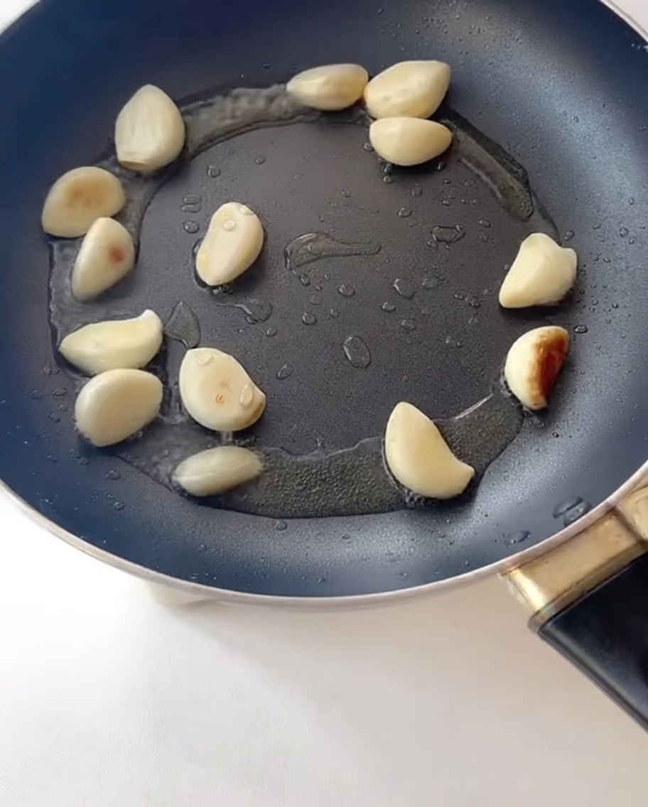 Fette di pancetta che friggono in padella insieme allaglio soffritto.