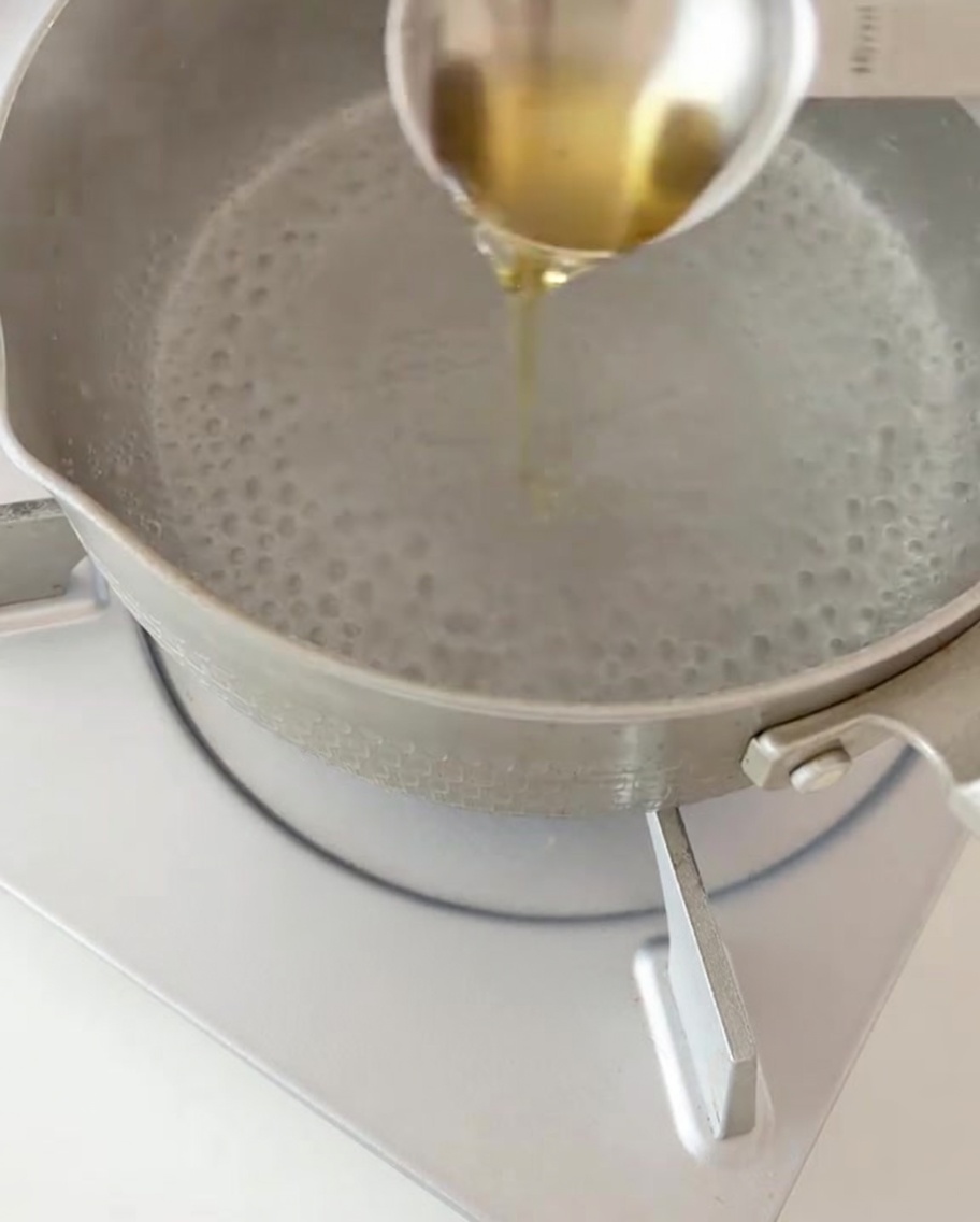 Fusilli secchi versati in una pentola di acqua bollente con un filo dolio.