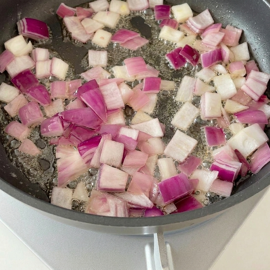Pezzi di pancetta che friggono in padella con la cipolla soffritta.