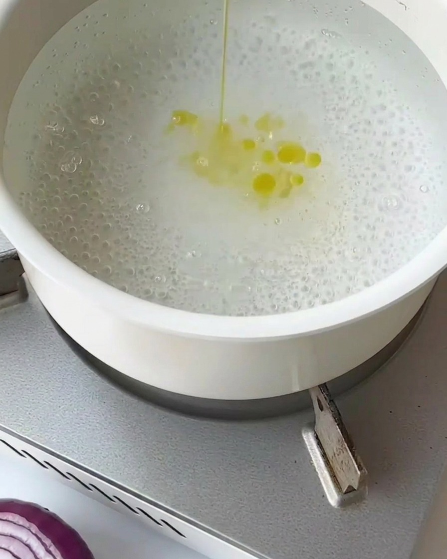 Segmenti di asparagi sbollentati in acqua bollente allinterno di un colino a maglia fine.