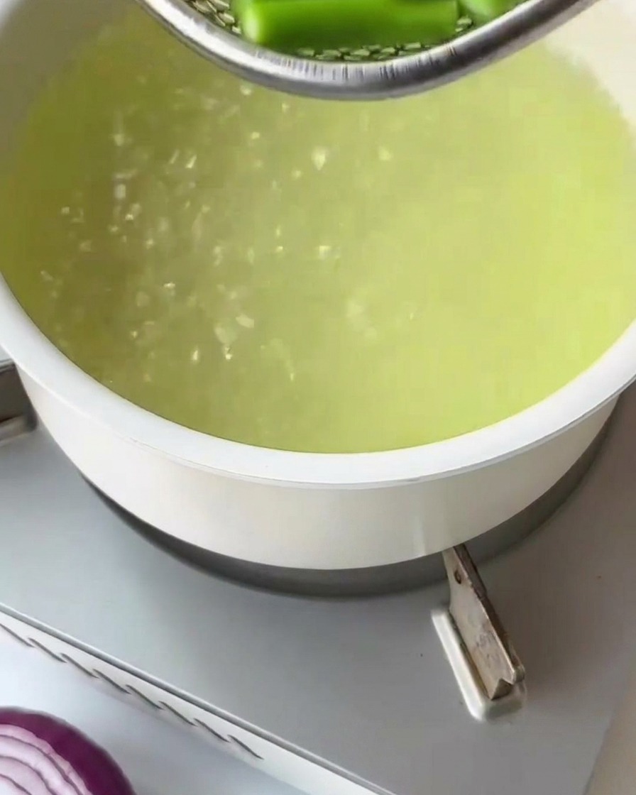 Fusilli secchi versati in una pentola di acqua bollente.