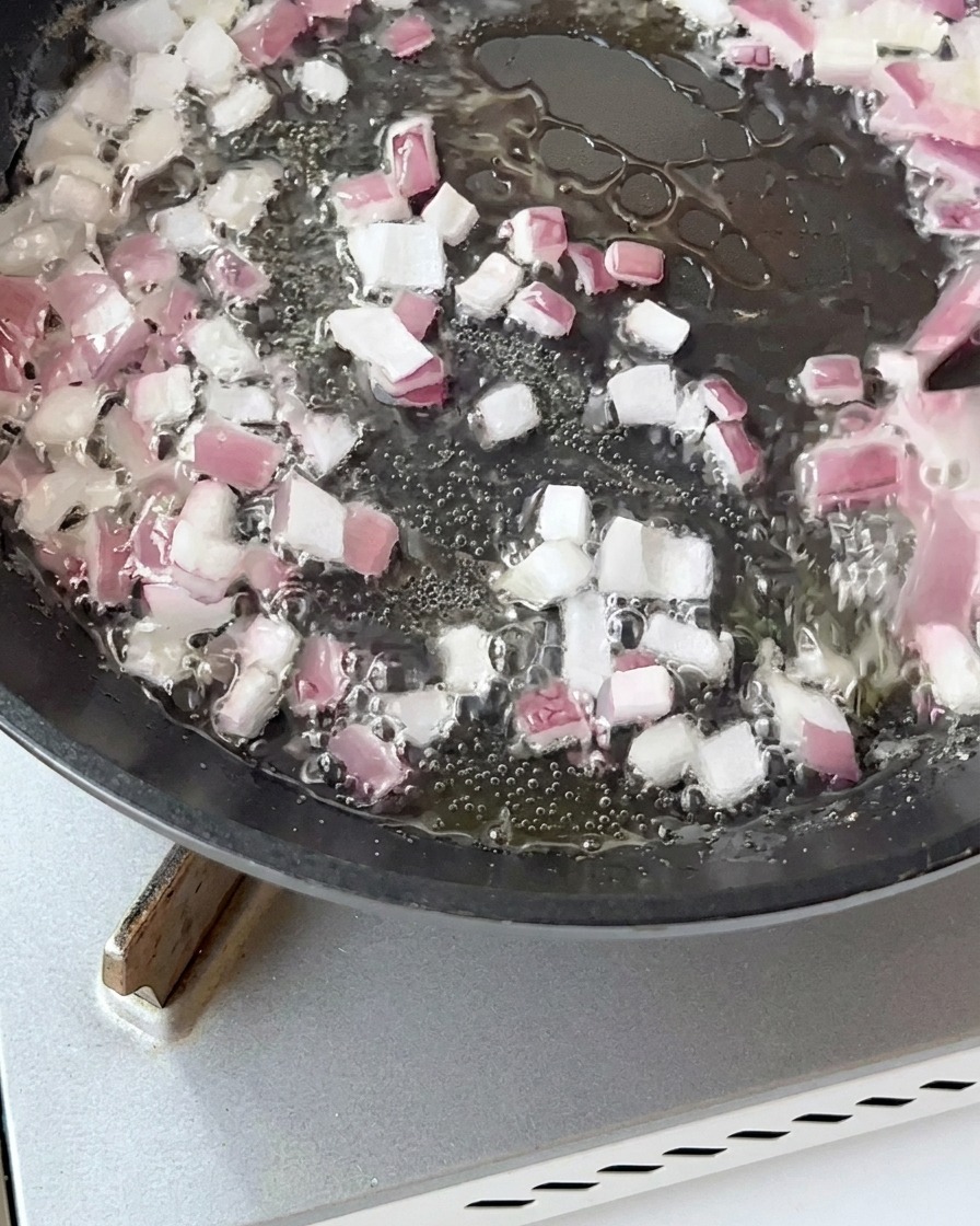 Pezzi di pancetta saltati in padella con cipolla fino a doratura.