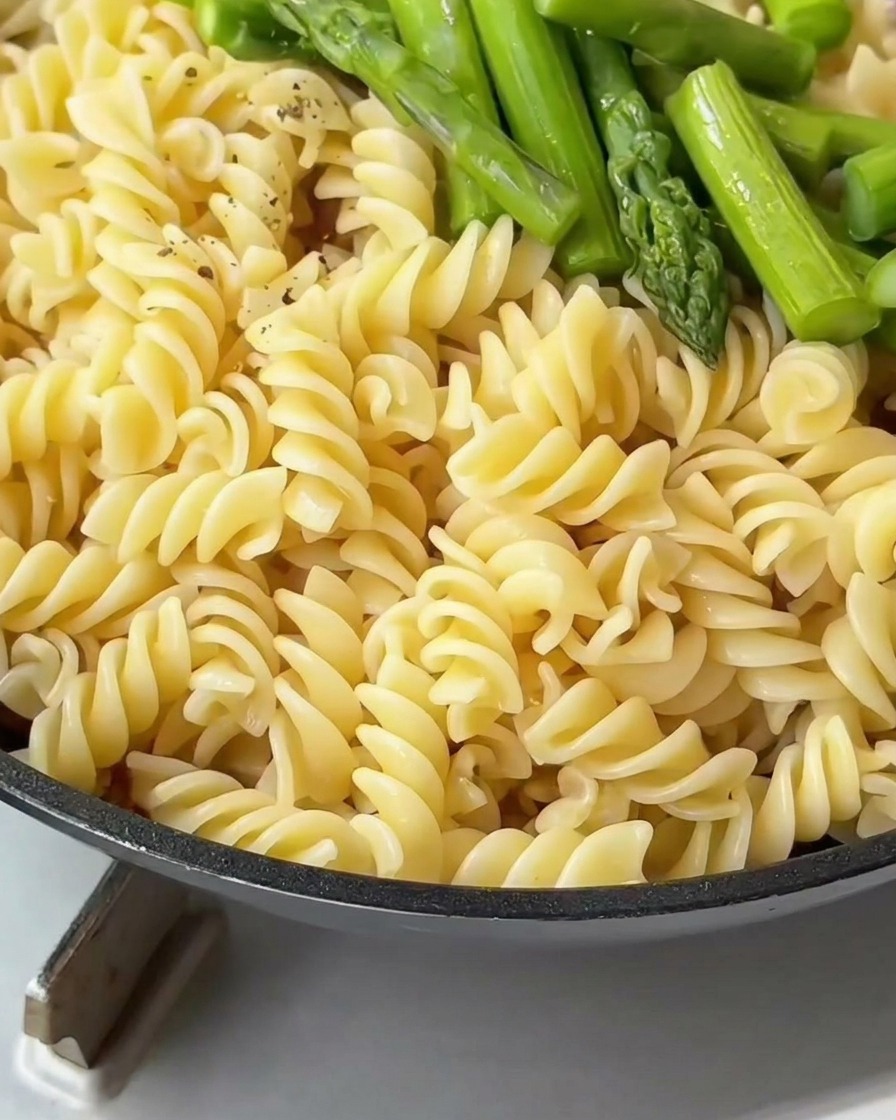 Fusilli e asparagi in padella conditi con pepe nero appena macinato.