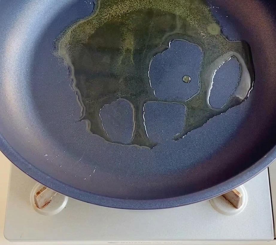 Cipolla rossa a dadini che cuoce in una padella con olio caldo.
