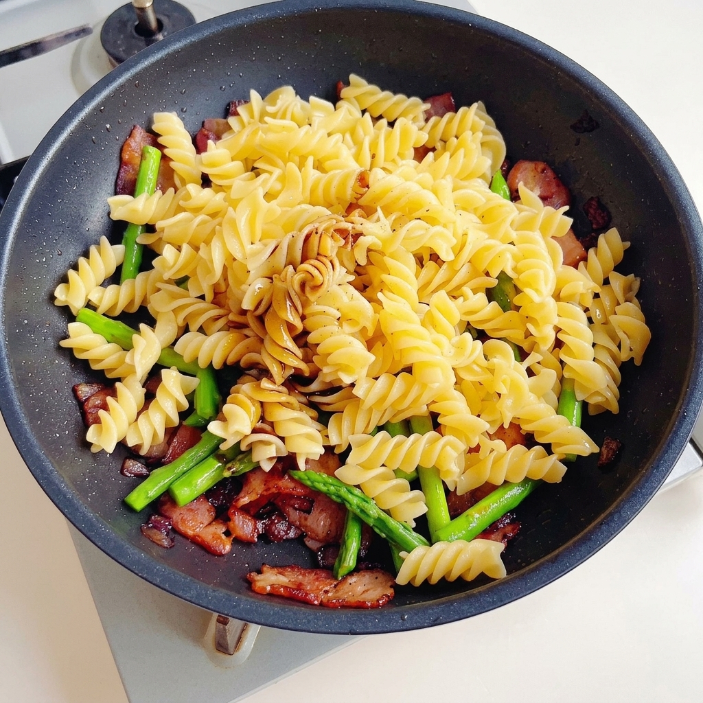 Salsa di soia, salsa di soia scura e salsa di ostriche versate su un misto di pasta, pancetta e asparagi.