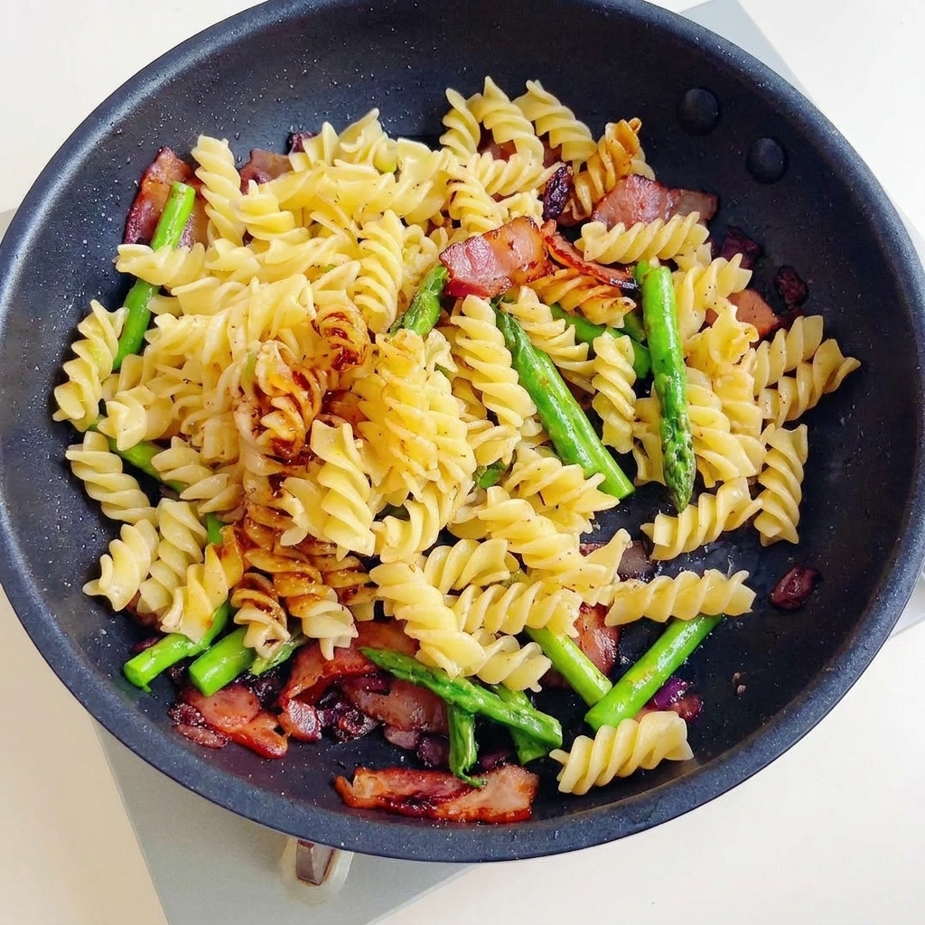 Un delizioso soffritto di fusilli, pancetta croccante e asparagi saltati in una salsa scura e saporita.