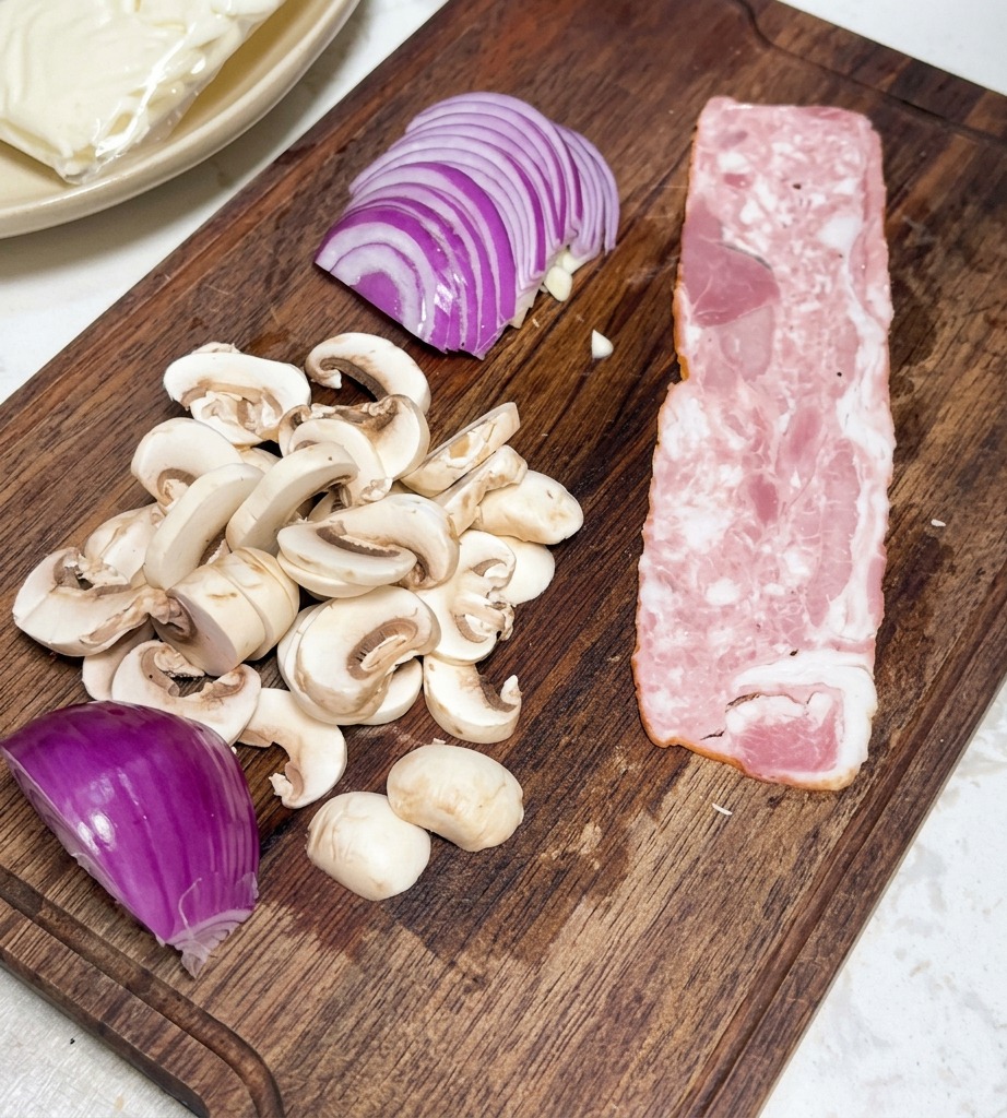 Strisce di bacon tagliate in rettangoli regolari pronti sul tagliere.
