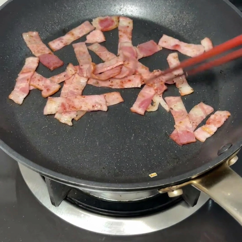 Una noce di burro che si scioglie nella padella insieme al bacon rosolato.