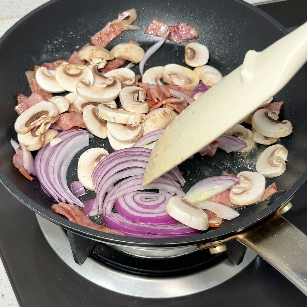 Cipolla rossa e funghi che soffriggono in padella con bacon e burro.