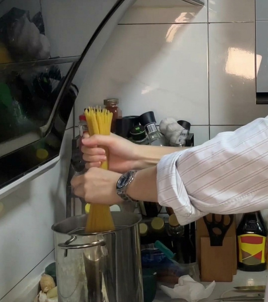 Spaghetti inseriti in una pentola di acqua bollente con olio e sale.