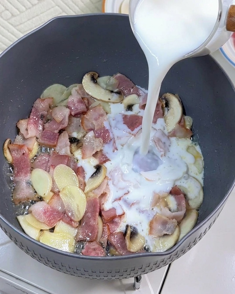 Il latte viene versato nella padella con pancetta e funghi rosolati.