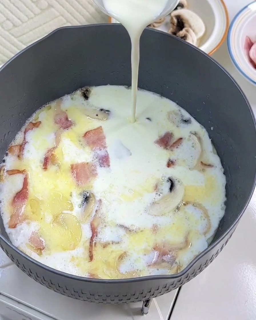 La panna fresca viene aggiunta alla padella con latte, pancetta e funghi.