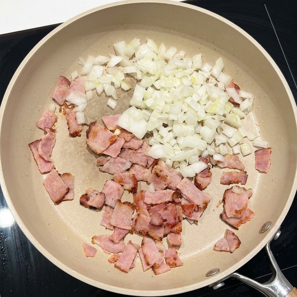 Cipolle bianche tritate saltate in padella con pezzi di pancetta.