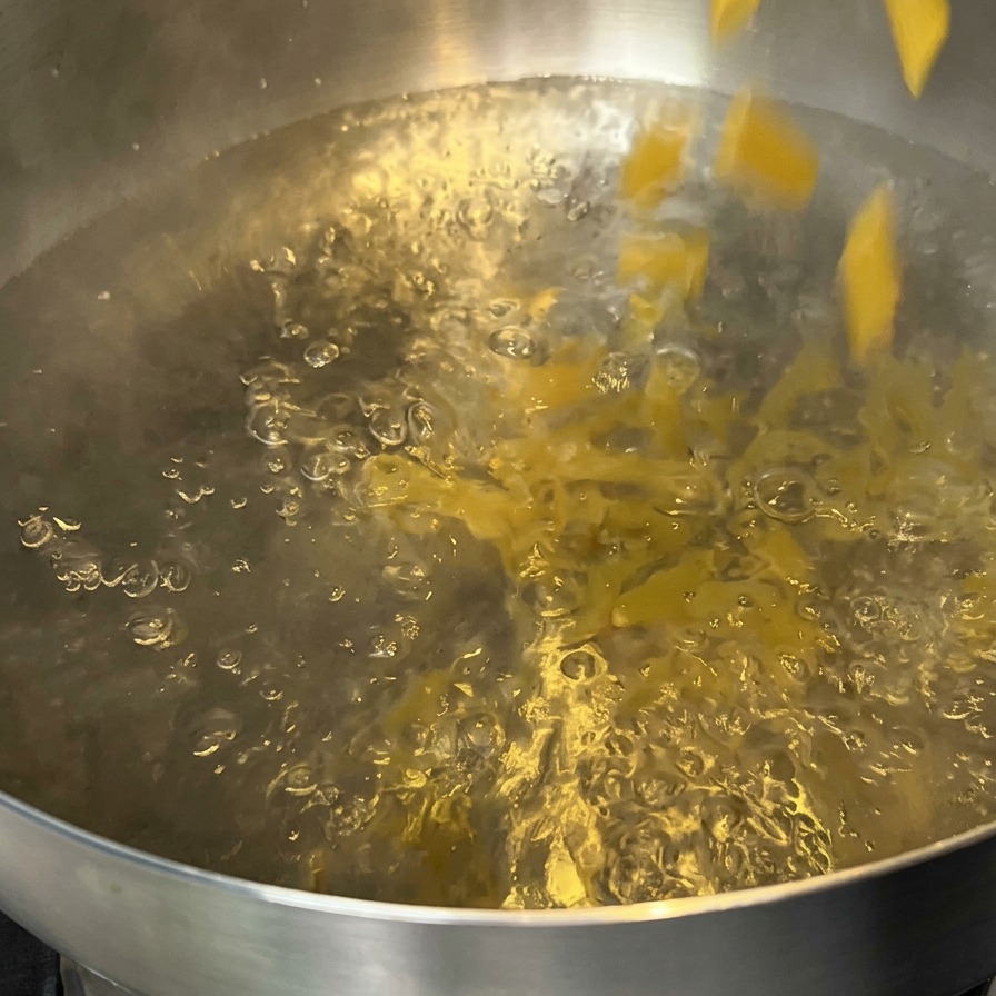 Penne versate in una pentola di acqua bollente.