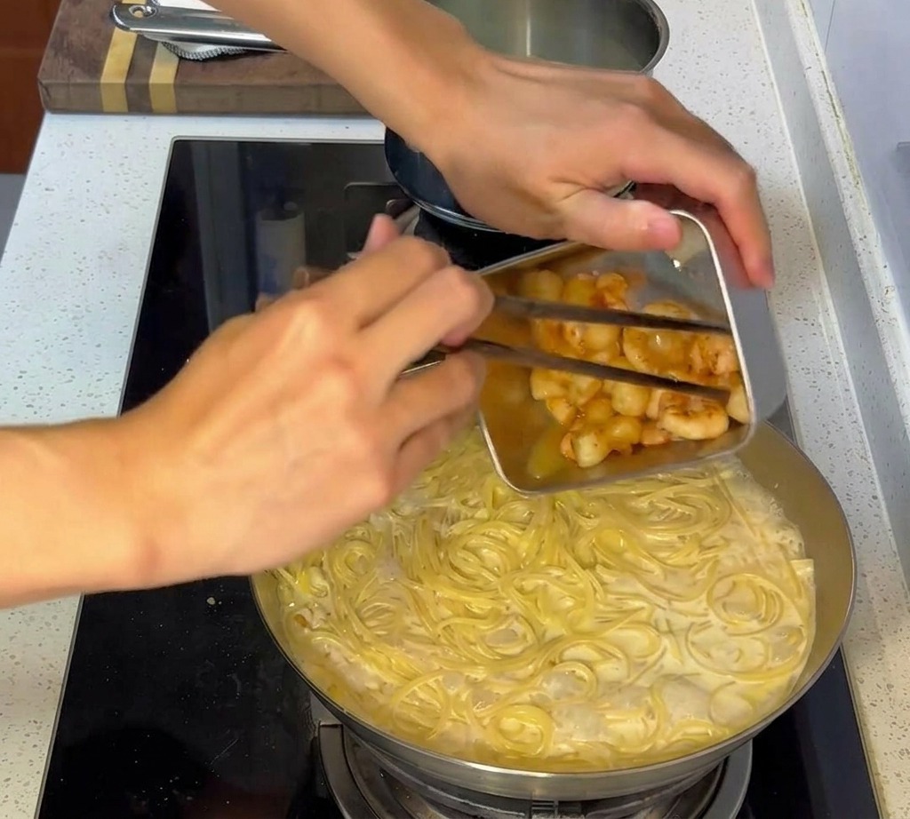 Frutti di mare cotti in padella aggiunti al mix di pasta cremosa.