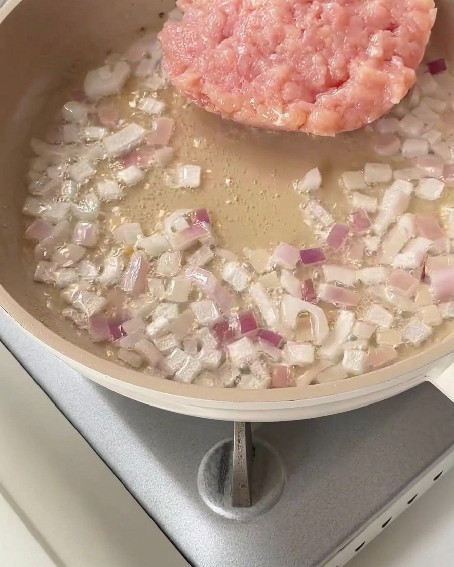 Pollo macinato crudo aggiunto in padella con le cipolle saltate.