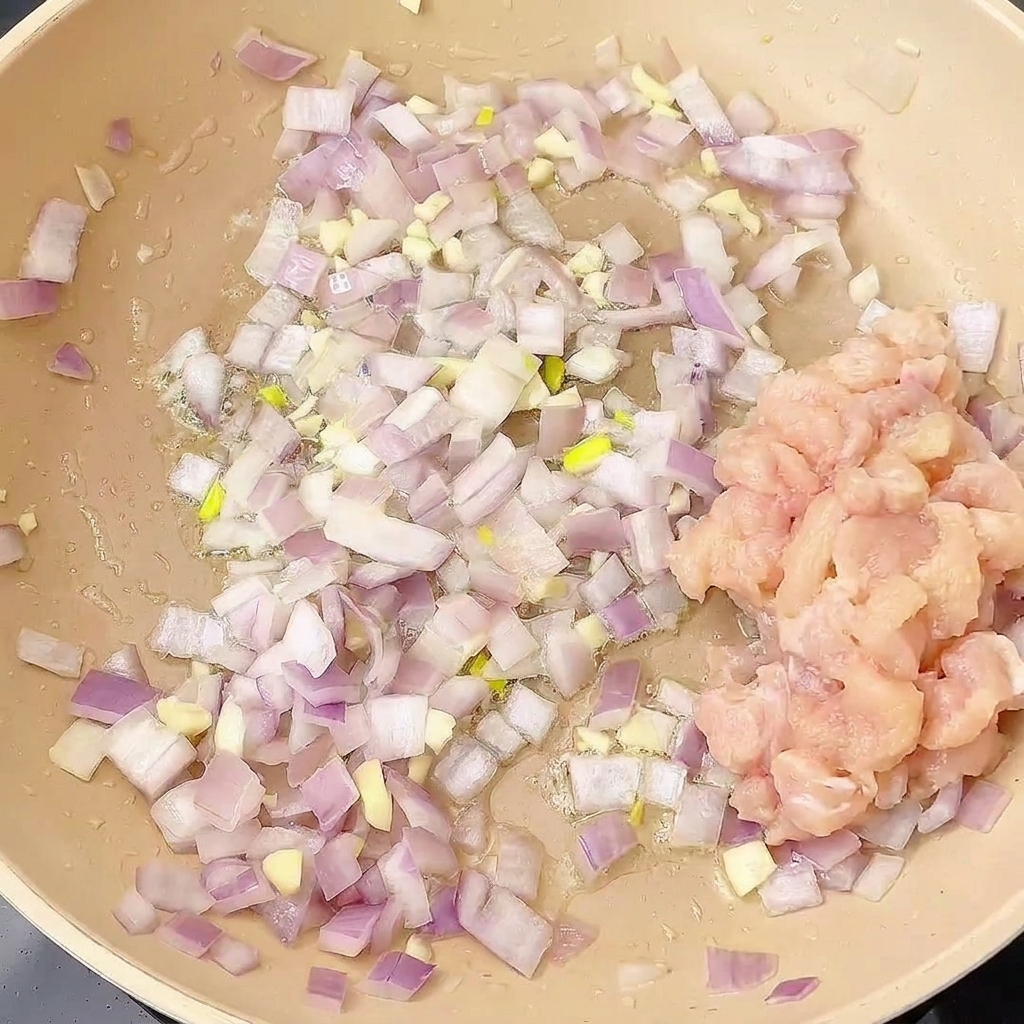 Pollo a dadini aggiunto nella padella con il soffritto di cipolla e aglio.