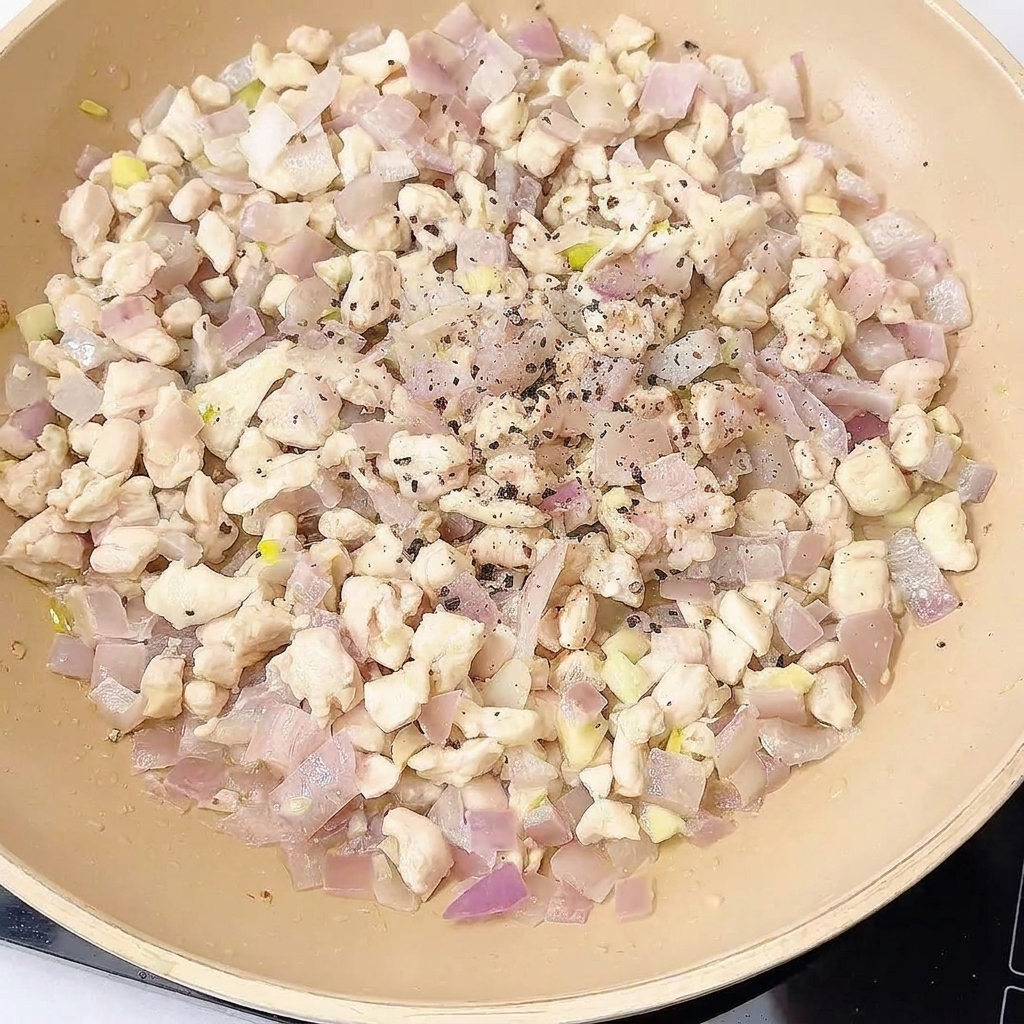 Il pollo in padella viene condito con spezie e salse.