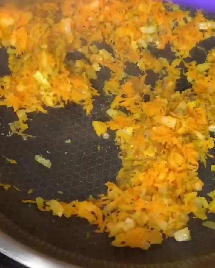 Macinato di manzo mescolato con carote e cipolle soffritte in una padella antiaderente.