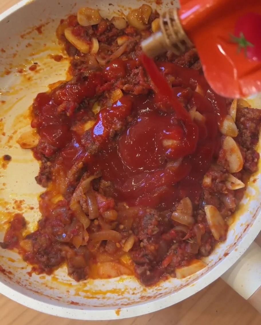 Salsa piccante messicana versata direttamente nella padella con carne e pomodori.