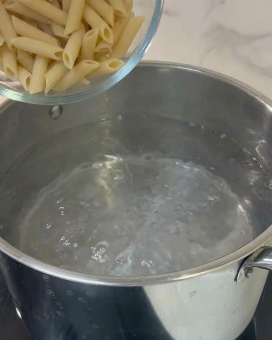 Penne versate in una pentola di acqua bollente.