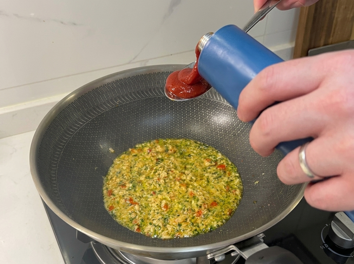 Passata di pomodoro versata in una padella con tonno e aromi.
