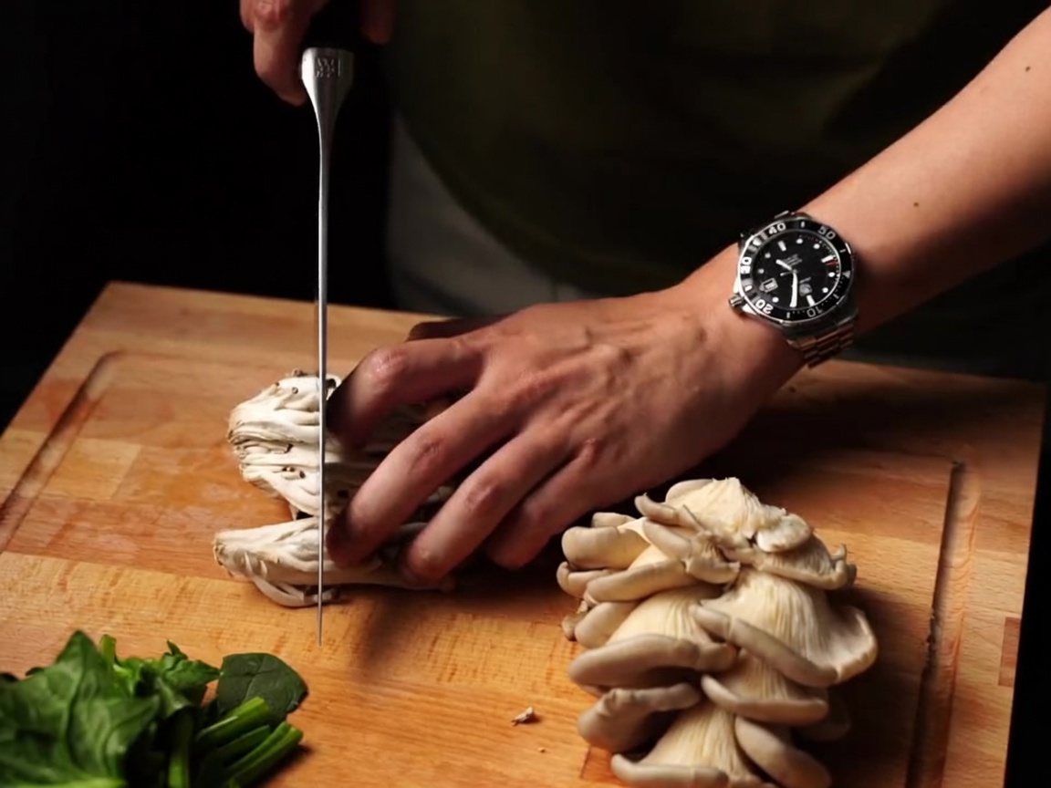 Funghi freschi tagliati a fette con un coltello su un tagliere.