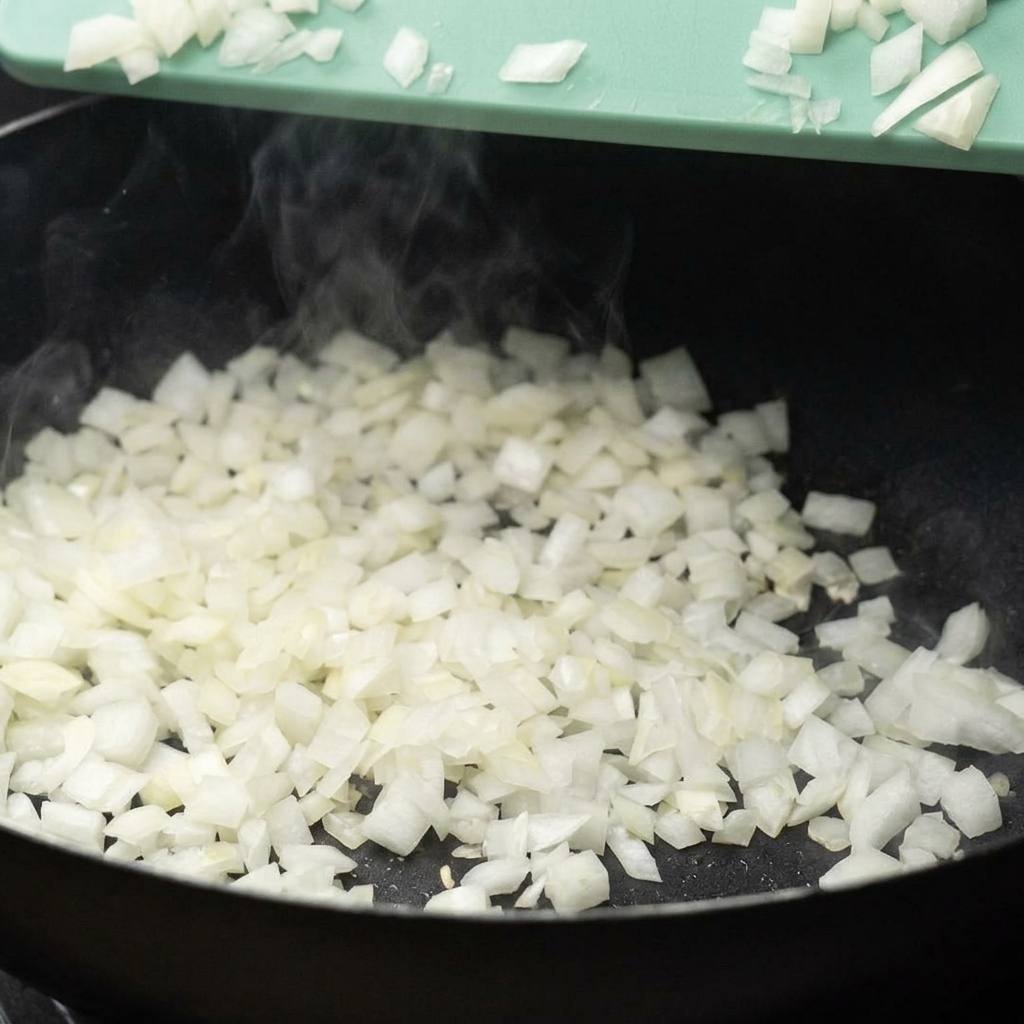 Cipolla tritata versata da un tagliere in una padella calda.