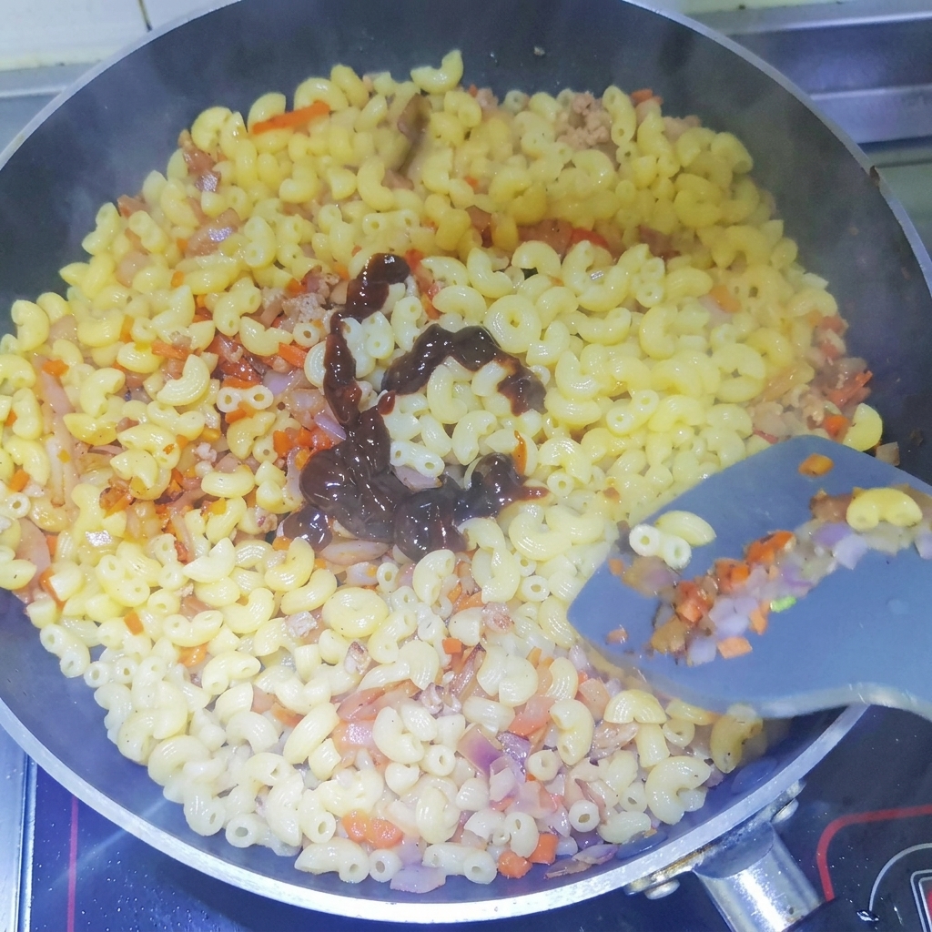 Salsa scura al pepe nero spruzzata a spirale sui maccheroni cotti in padella.