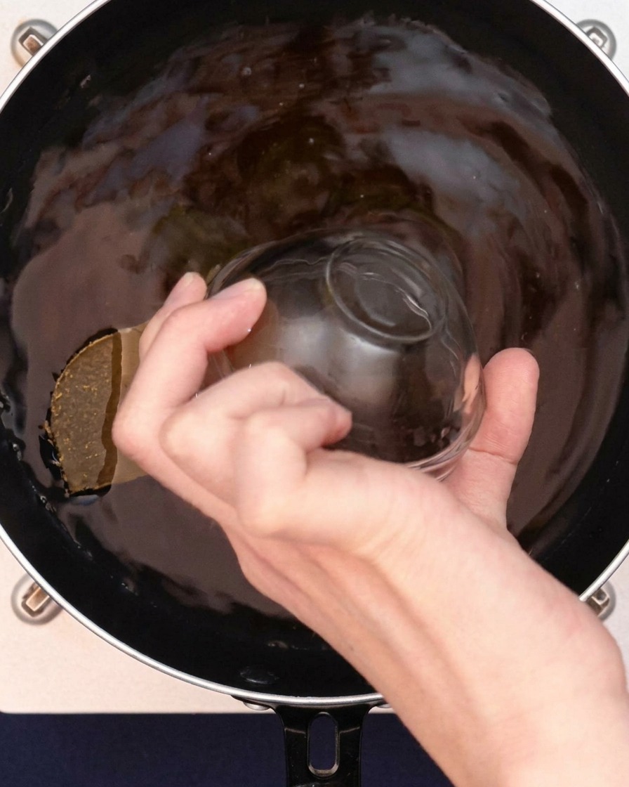 Granuli di brodo chiaro che vengono sparsi nel brodo al curry.