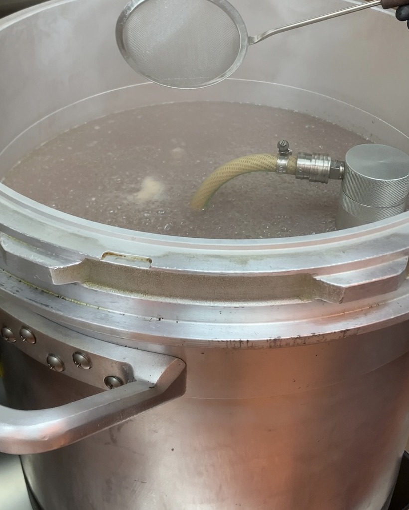 Rimozione della schiuma dalla superficie del brodo in ebollizione usando una schiumarola.
