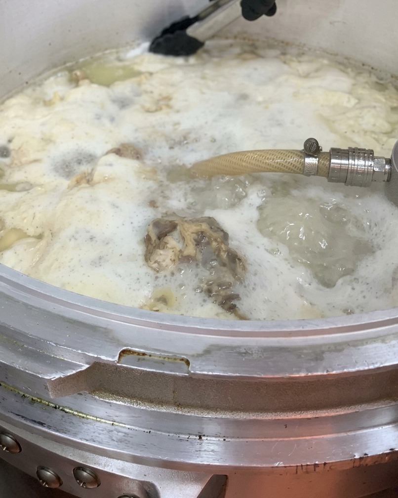 Olio di pollo versato nella grande pentola di brodo.