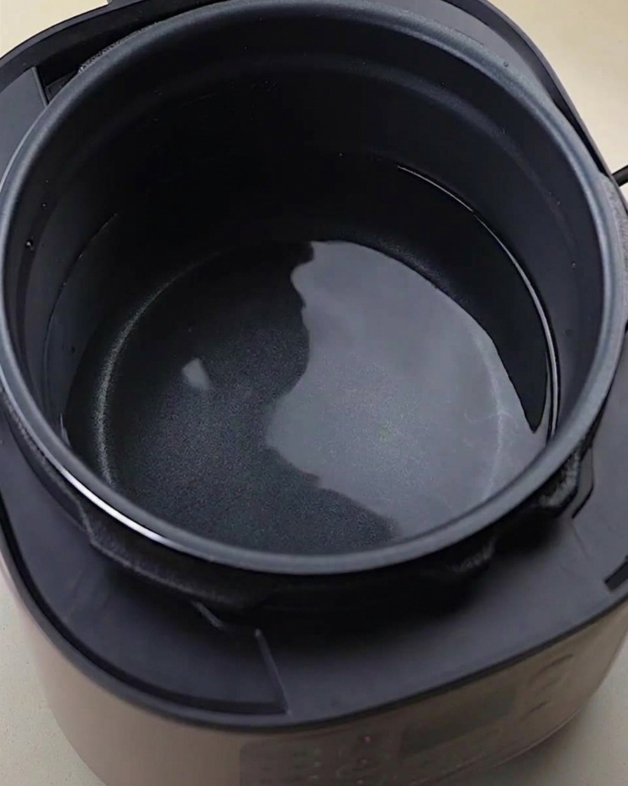 Ossa, ali e zampe di pollo crude allinterno di una pentola a pressione con acqua