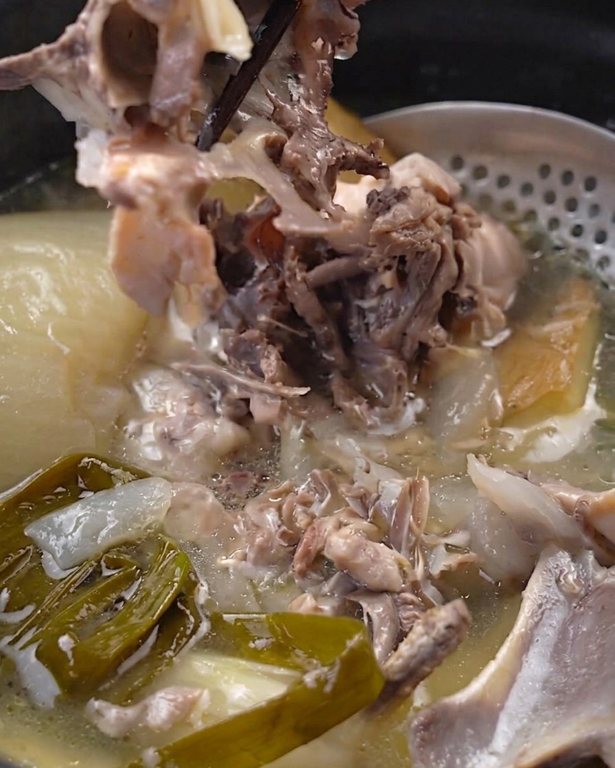 Bacchette che separano la carne di pollo tenera e cotta dallosso allinterno della pentola